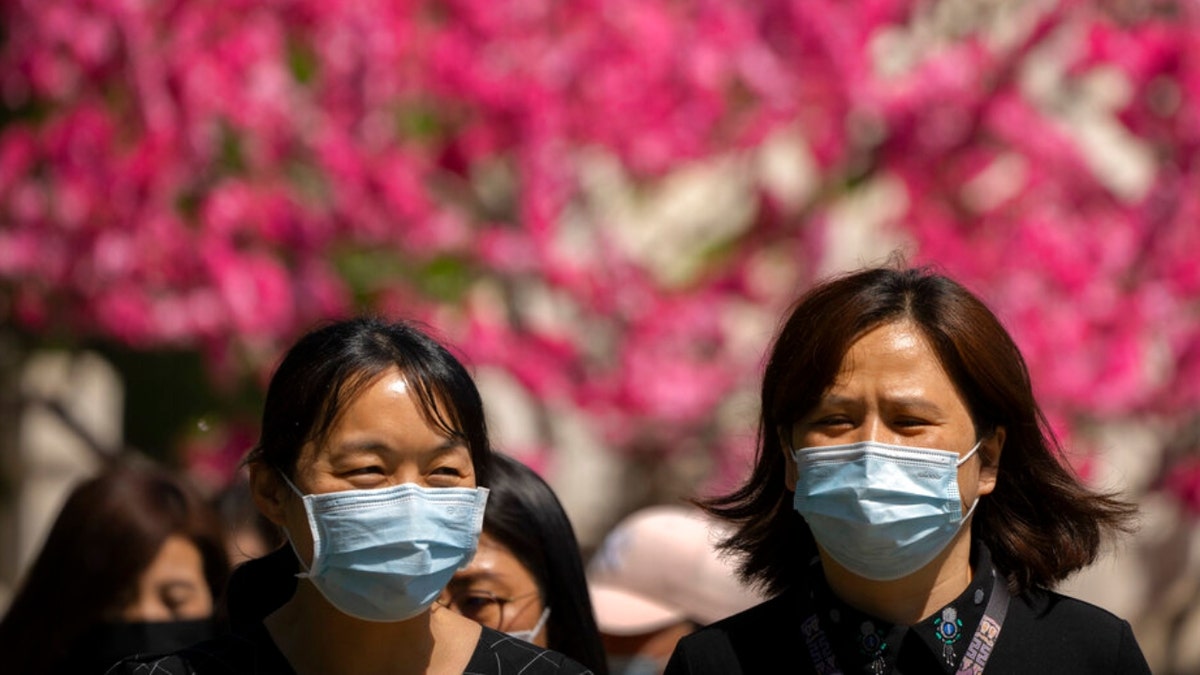 People wearing masks walk outside in Beijing