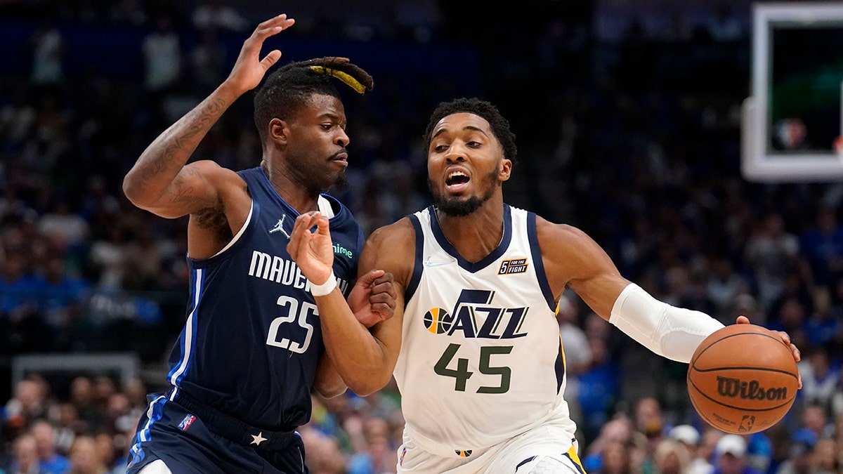 Dallas Mavericks forward Reggie Bullock (25) defends as Utah Jazz guard Donovan Mitchell (45) works to the basket in the first half of Game 1 of an NBA basketball first-round playoff series, Saturday, April 16, 2022, in Dallas.