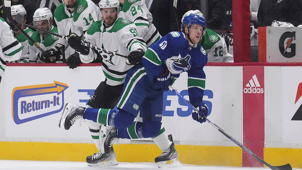 Dallas Stars' Tyler Seguin, left, checks Vancouver Canucks' Elias Pettersson, of Sweden, during the first period of an NHL hockey game in Vancouver, British Columbia, Monday, April 18, 2022.