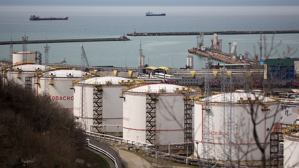 Oil storage tanks stand at the RN-Tuapsinsky refinery, operated by Rosneft Oil Co., as tankers sail beyond in Tuapse, Russia, on Monday, March 23, 2020.