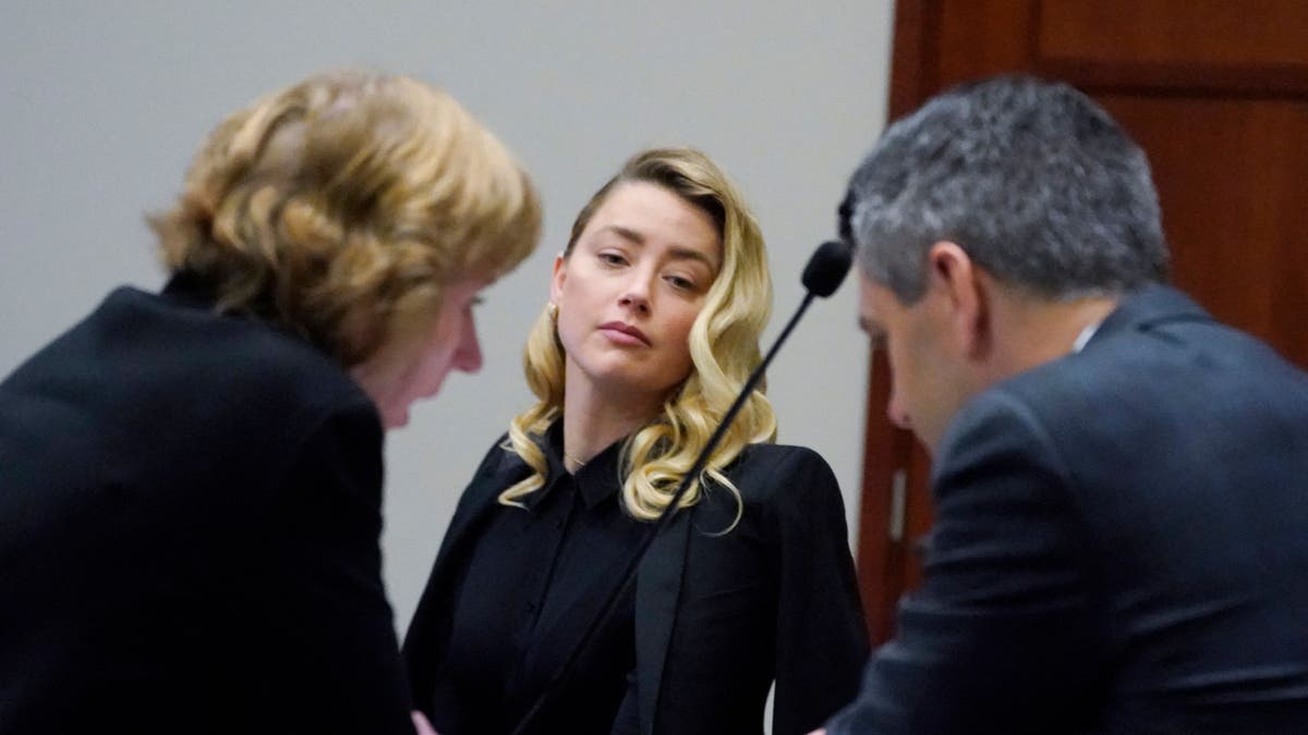 Amber Heard looks at her lawyers Elaine Bredehoft and Ben Rottenborn in court