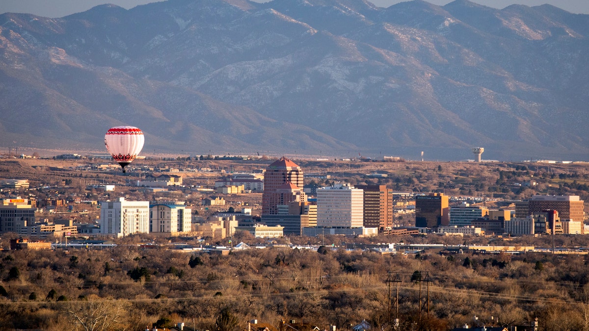 A hot air balloon floats over the skyscrapers of downtown Albuquerque, New Mexico.