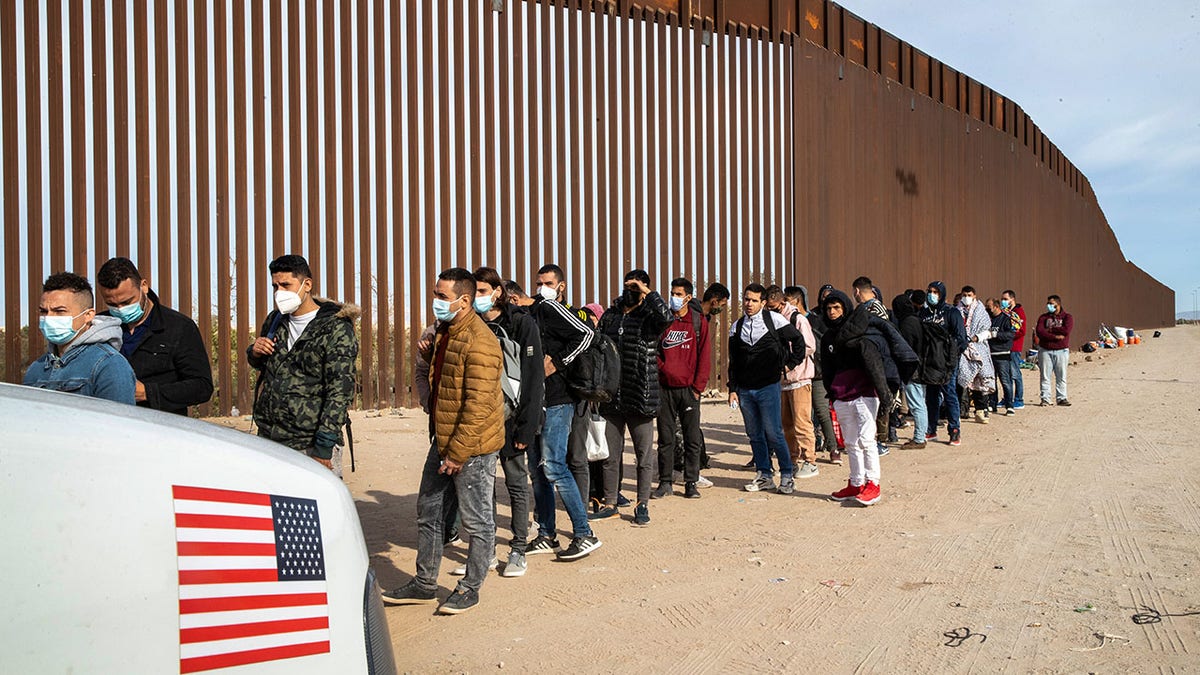 Migrants lined up at border wall