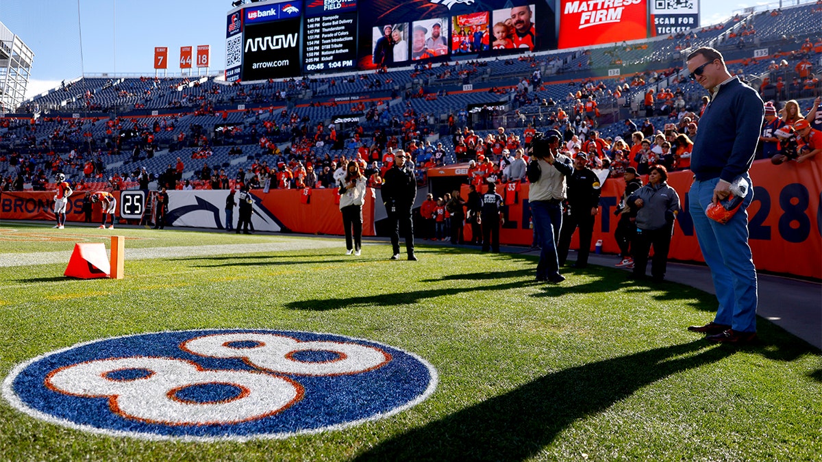 Former Denver Broncos player Peyton Manning (R) looks to the #88 logo on the field, in memory of his former Denver Broncos teammate Demaryius Thomas, before the game between the Detroit Lions and the Denver Broncos on December 9 at Empower Field At Mile High on December 12, 2021 in Denver, Colorado.