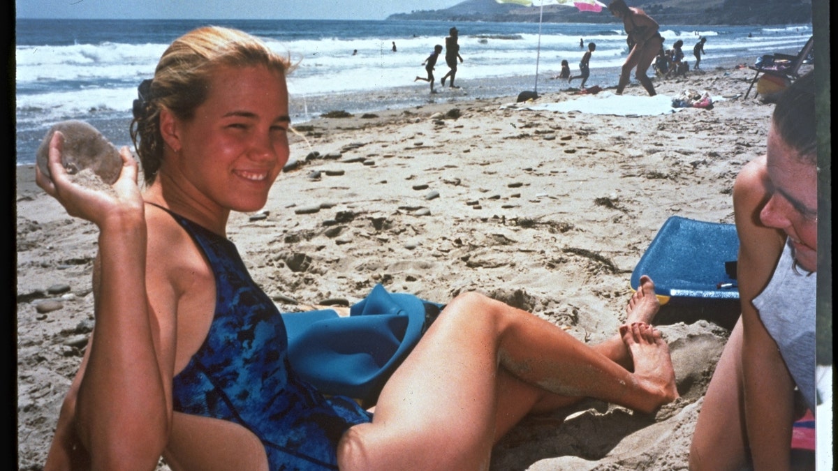 Kristin Smart smiling in a blue swimsuit by the beach