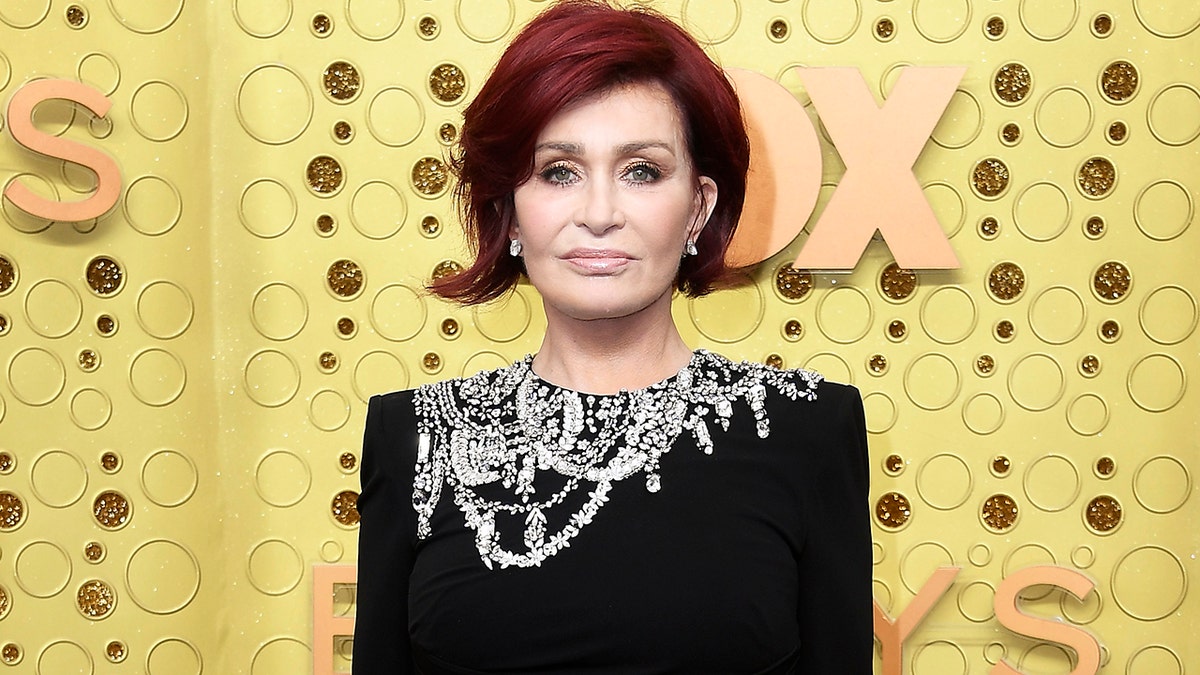 Sharon Osbourne with a short bob haircut and a black dress with stones on the top of the dress