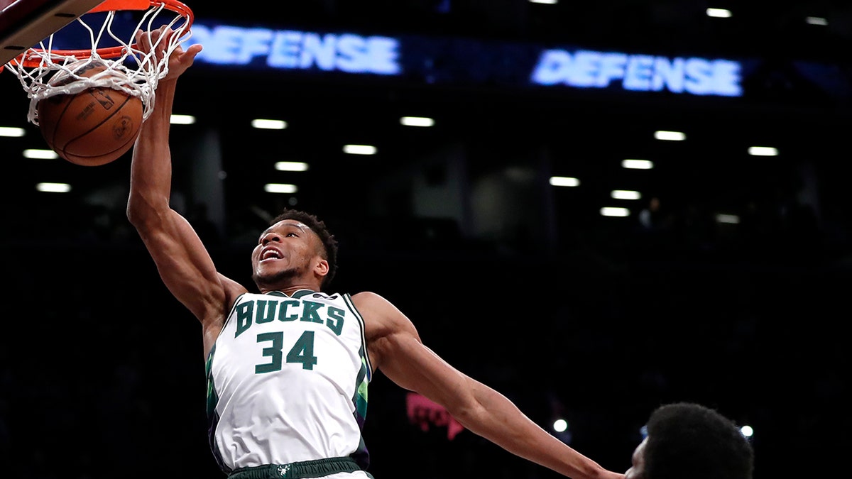 Milwaukee Bucks forward Giannis Antetokounmpo (34) dunks as Brooklyn Nets Kevin Durant (7) and Kyrie Irving watch during the first half of an NBA basketball game Thursday, March 31, 2022, in New York.