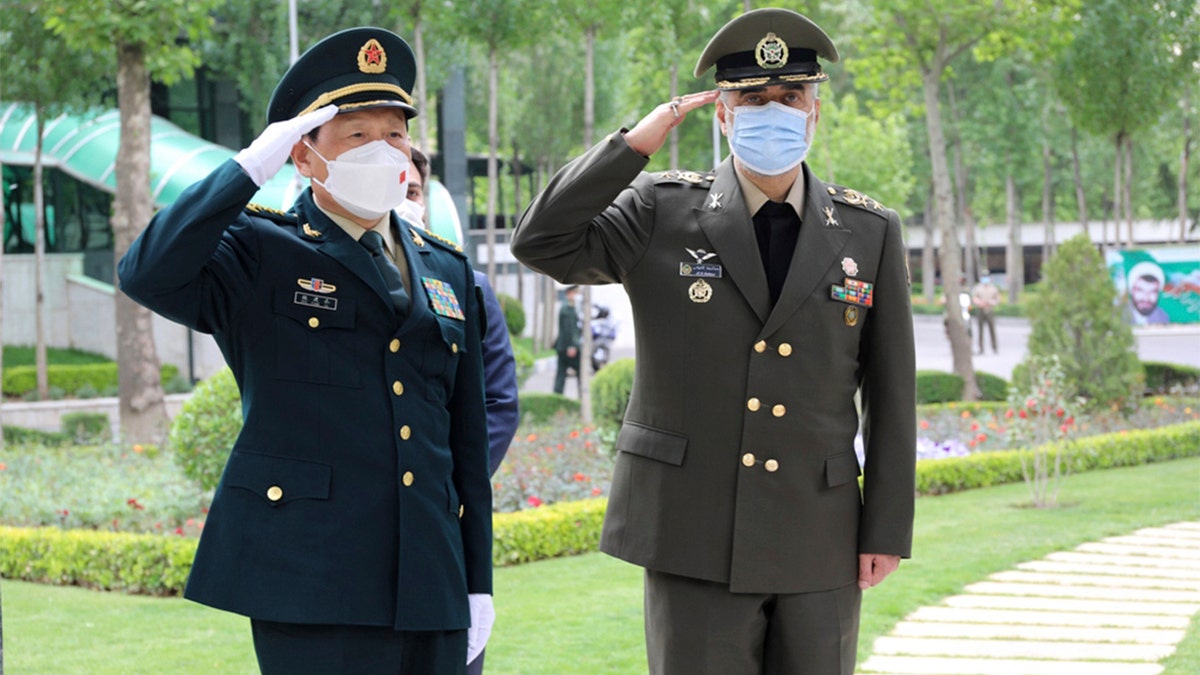 In this picture released by the official website of the Iranian Defense Ministry, China's minister of national defense Gen. Wei Fenghe, left, is welcomed by Iran's defense minister Gen. Mohammad Reza Ashtiani, during an official welcoming ceremony, in Tehran, Iran, Wednesday, April 27, 2022. (Iranian Defense Ministry via AP)