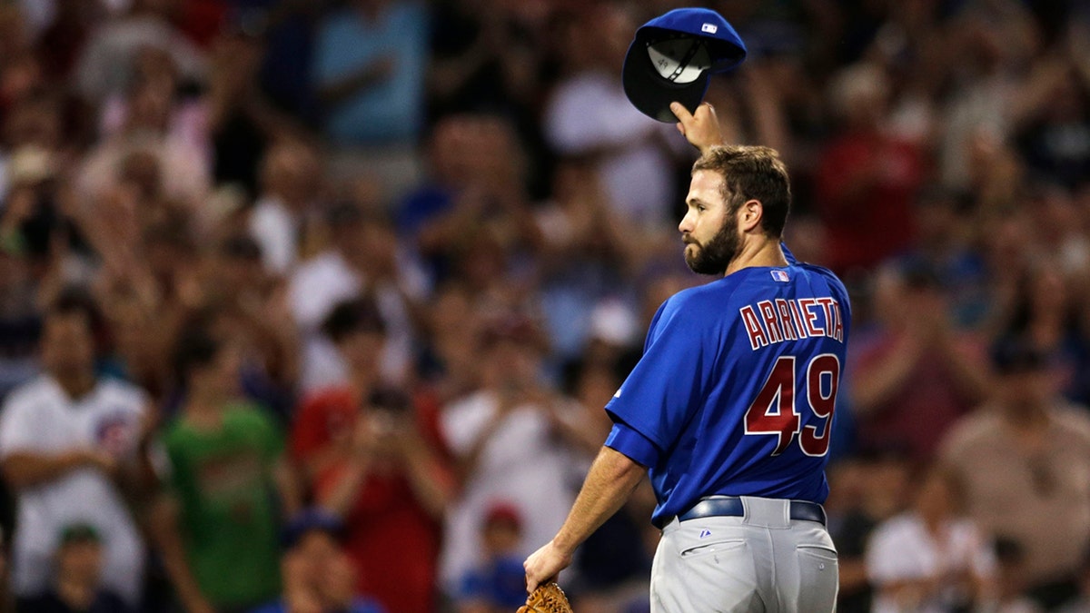 FILE - Chicago Cubs starting pitcher Jake Arrieta tips his cap as he gets a standing ovation from Red Sox fans after carrying a no-hitter to the eighth inning of a baseball game at Fenway Park in Boston, Monday, June 30, 2014.