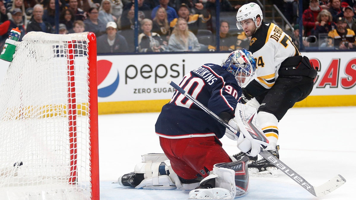 Boston Bruins forward Jake DeBrusk, right, scores past Columbus Blue Jackets goalie Elvis Merzlikins during the first period of an NHL hockey game in Columbus, Ohio, Monday, April 4, 2022.