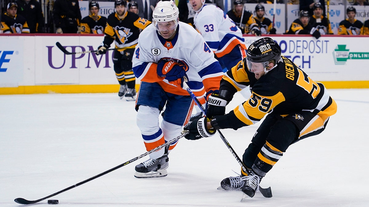 Pittsburgh Penguins' Jake Guentzel (59) tries to get the puck past New York Islanders' Andy Greene (4) during the second period of an NHL hockey game Thursday, April 14, 2022, in Pittsburgh.