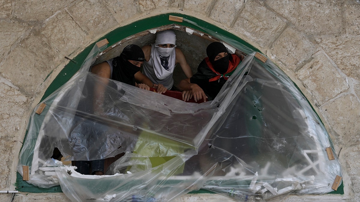 Masked Palestinians take position during clash with Israeli security forces at the Al Aqsa Mosque compound in Jerusalem's Old City Friday, April 15, 2022. (AP Photo/Mahmoud Illean)