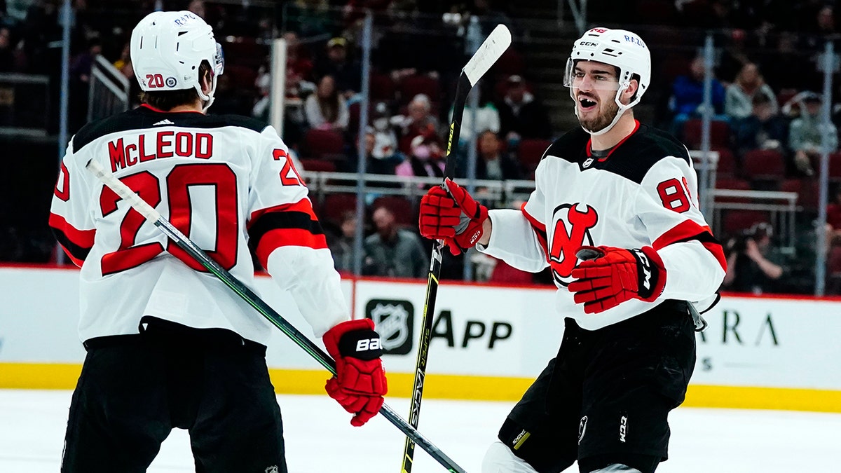 New Jersey Devils defenseman Kevin Bahl, right, celebrates his first NHL goal with center Michael McLeod (20) during the second period of the team's NHL hockey game against the Arizona Coyotes on Tuesday, April 12, 2022, in Glendale, Ariz. 