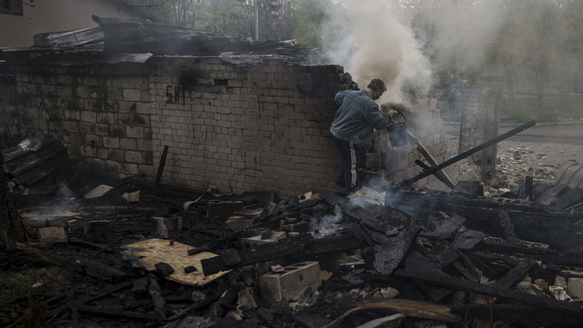 A man tries to extinguish a fire following a Russian bombardment at a residential neighborhood in Kharkiv, Ukraine, on Wednesday.