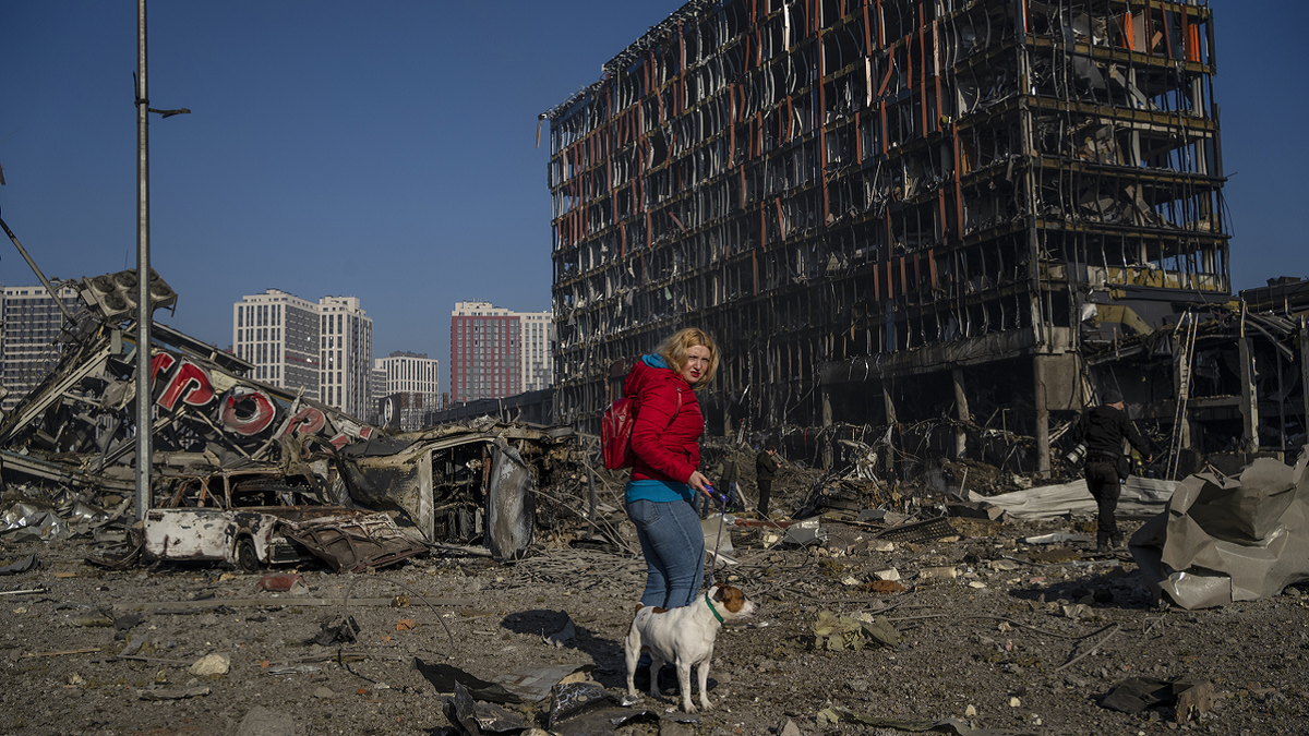 Irina Zubchenko walks with her dog Max amid the destruction caused after shelling of a shopping center, in Kyiv, Ukraine, on Monday.