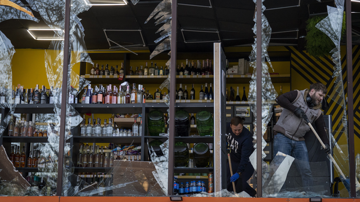 Employees at a liquor store clean glass broken following the explosion on Thursday, April 28.