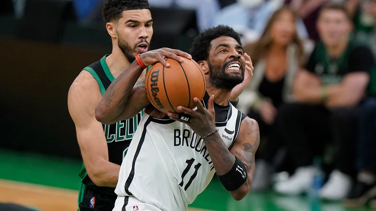 Brooklyn Nets guard Kyrie Irving (11) drives toward the basket as Boston Celtics forward Jayson Tatum (0) defends in the second half of Game 1 of an NBA basketball first-round Eastern Conference playoff series, Sunday, April 17, 2022, in Boston. The Celtics won 115-114.