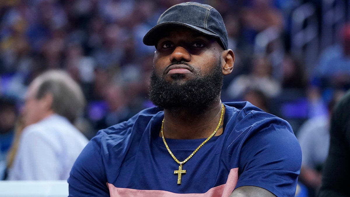 LeBron James in a blue jersey and ball cap looks on