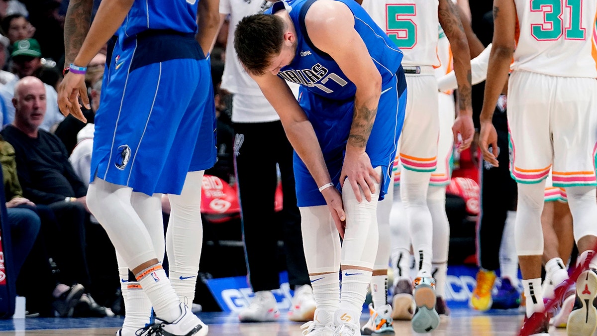 Dallas Mavericks' Luka Doncic (77) reaches for his lower leg after suffering an unknown lower leg injury in the second half of an NBA basketball game against the San Antonio Spurs, Sunday, April 10, 2022, in Dallas.