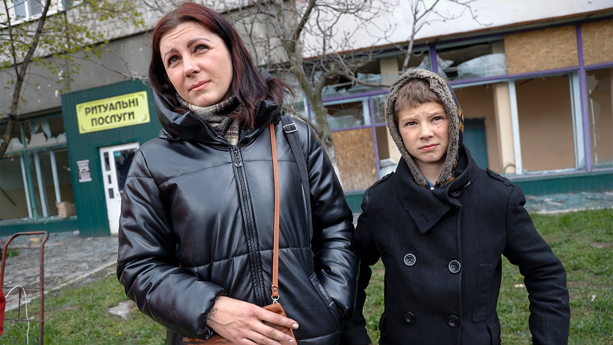 Local civilians, a mother and her son, speak to journalists in an area controlled by Russian-backed separatist forces in Mariupol, Ukraine, Friday, April 22, 2022. (AP Photo/Alexei Alexandrov)