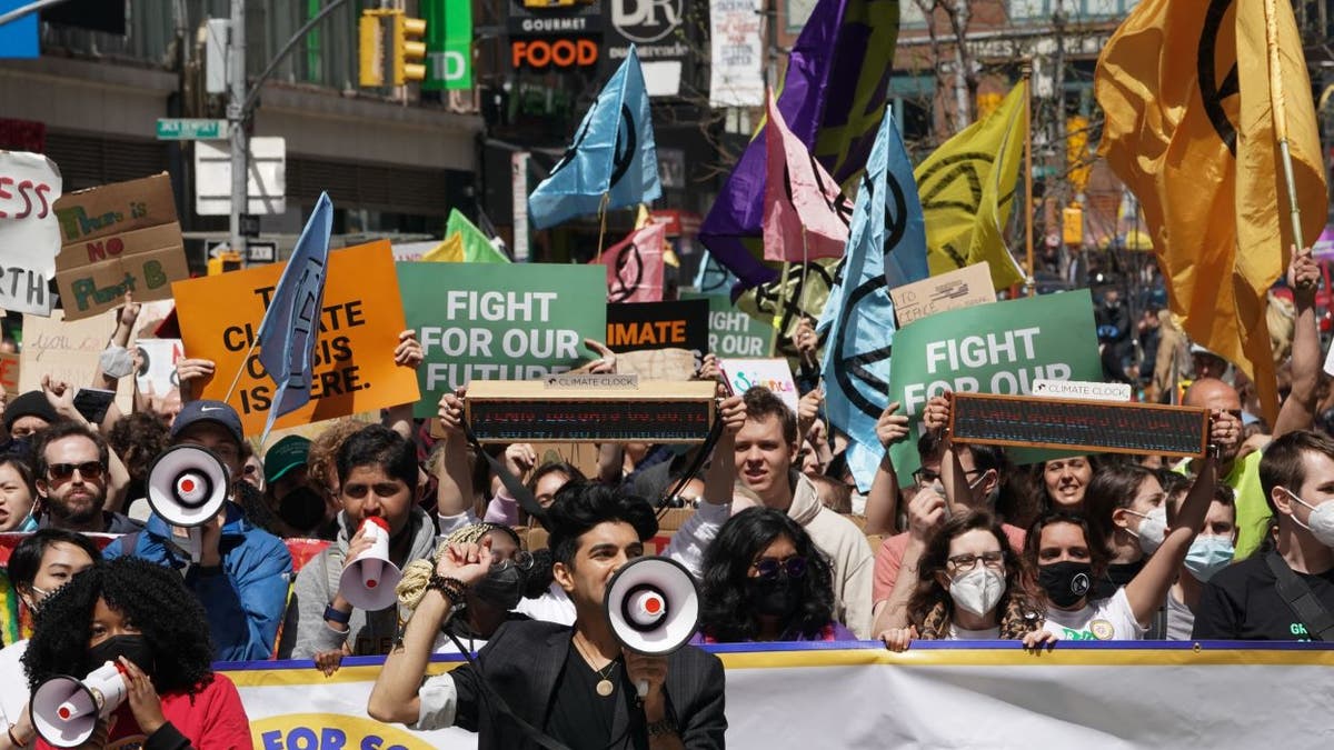 People carry signs at the March for Science in collaboration with Extinction Rebellion NYC and other organizations on April 23, 2022