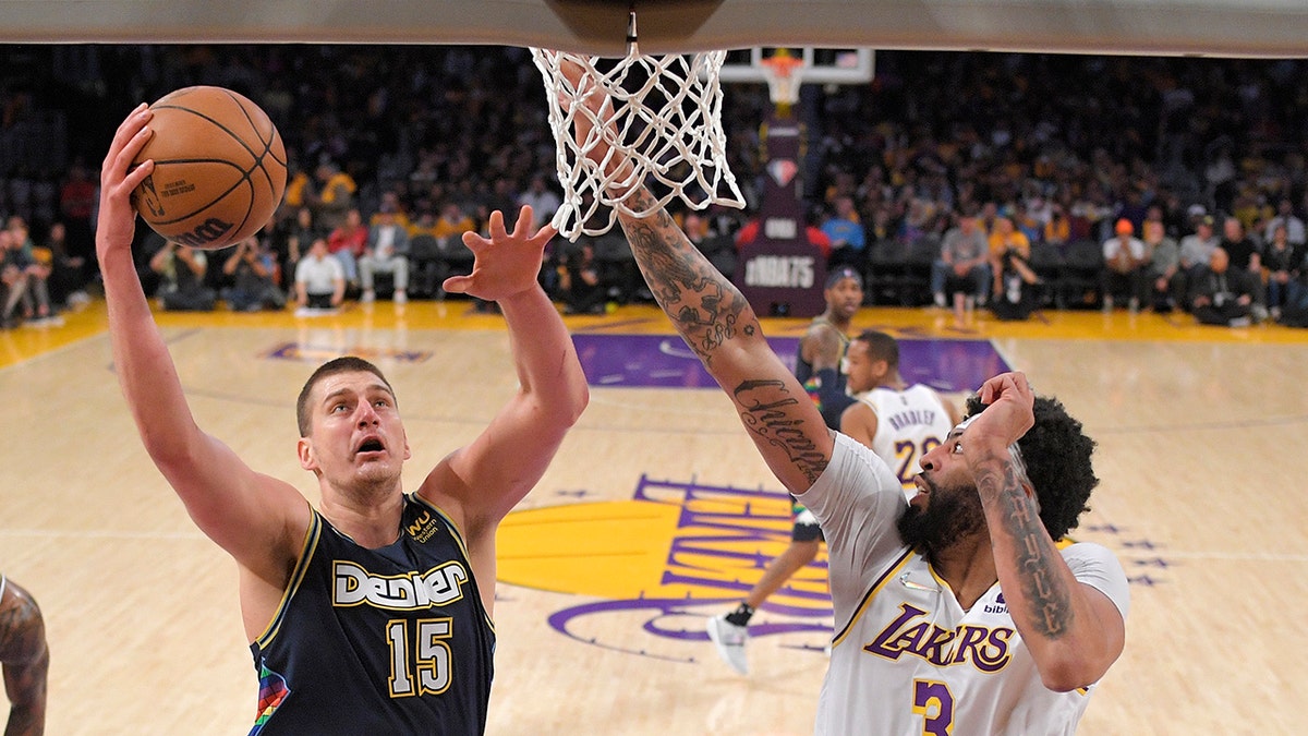 Denver Nuggets center Nikola Jokic, left, shoots as Los Angeles Lakers forward Anthony Davis defends during the first half of an NBA basketball game Sunday, April 3, 2022, in Los Angeles. 