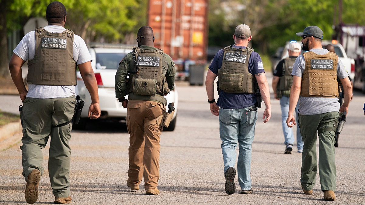 Members of the U.S. Marshals fugitive task force walk down a street near Columbiana Centre mall in Columbia, S.C., following a shooting, Saturday, April 16, 2022. (AP Photo/Sean Rayford)