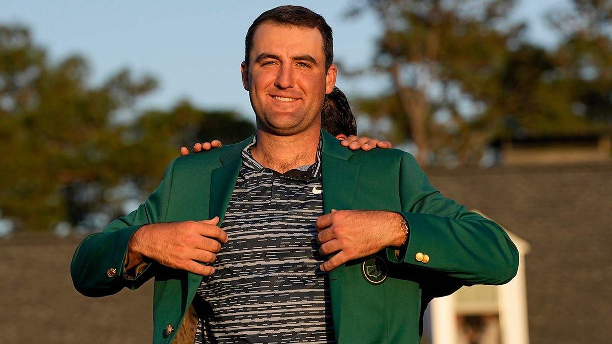 Hideki Matsuyama, of Japan, helps Scottie Scheffler put on the green jacket after winning the 86th Masters golf tournament on Sunday, April 10, 2022, in Augusta, Georgia.