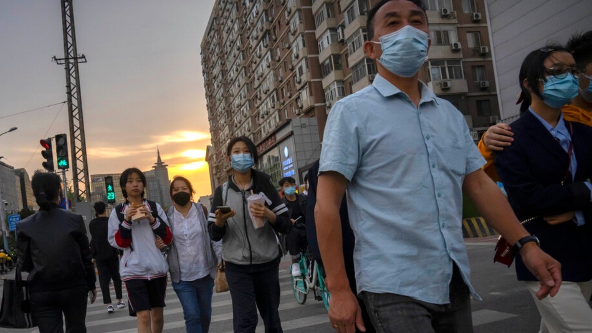 People wearing masks cross a Beijing intersection
