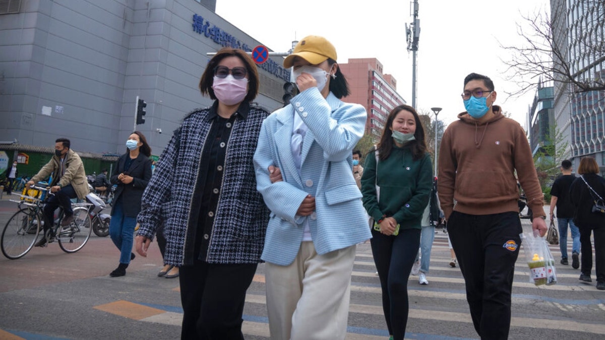 People walk across an intersection in Beijing