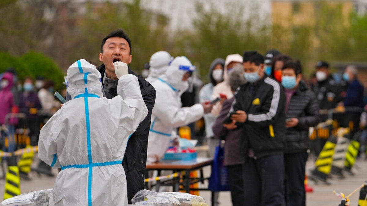 A health worker takes a throat swab from a Beijing man