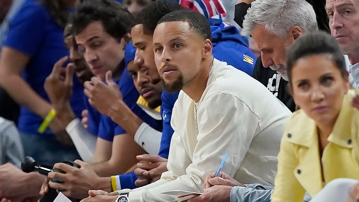 Golden State Warriors guard Stephen Curry, middle, watches during the first half of the team's NBA basketball game against the Los Angeles Lakers in San Francisco, Thursday, April 7, 2022.
