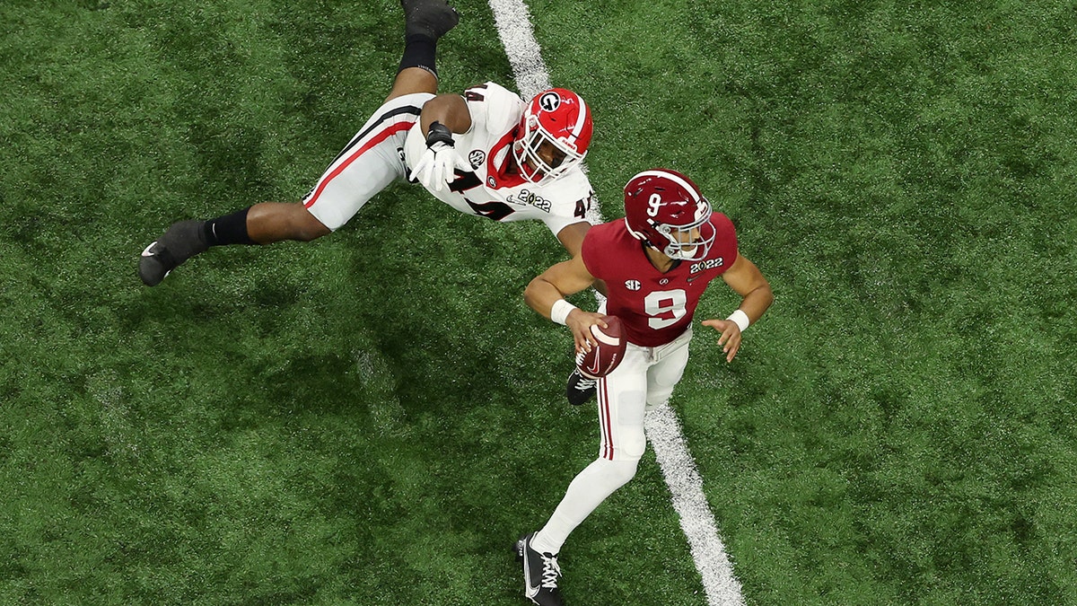 Bryce Young #9 of the Alabama Crimson Tide scrambles from Travon Walker #44 of the Georgia Bulldogs during the first quarter in the 2022 CFP National Championship Game at Lucas Oil Stadium on January 10, 2022, in Indianapolis, Indiana.