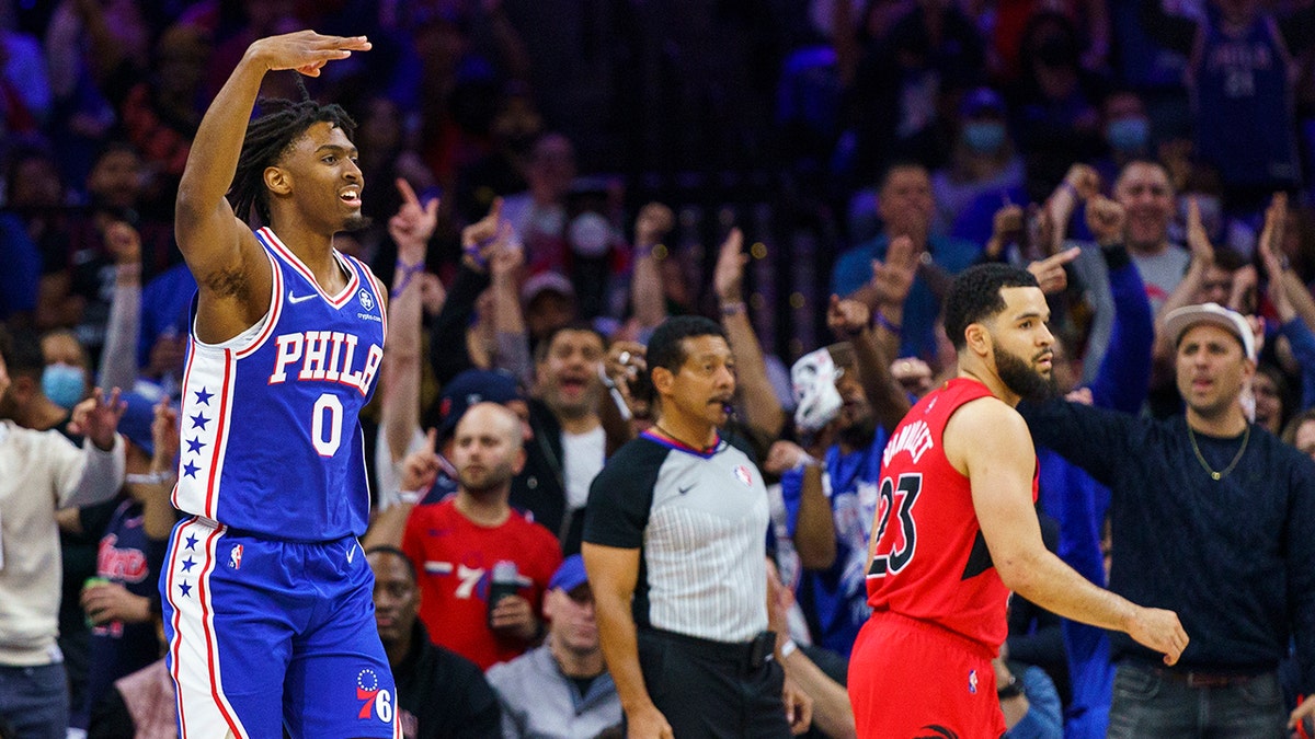 Philadelphia 76ers' Tyrese Maxey, left, reacts to his three-pointer as Toronto Raptors' Fred VanVleet, right, looks on during the first half of Game 1 of an NBA basketball first-round playoff series, Saturday, April 16, 2022, in Philadelphia.