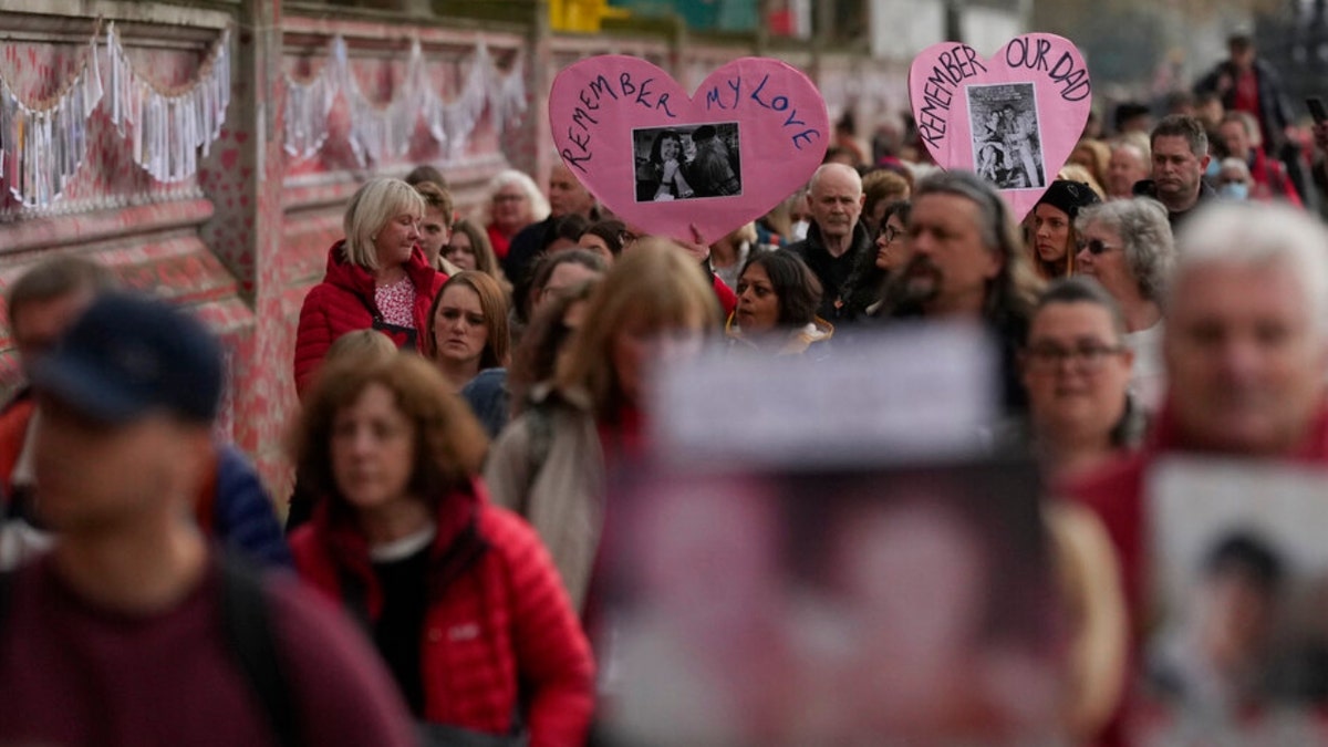 Family members of people who died of COVID-19 walk past London's National Covid Memorial wall in London.