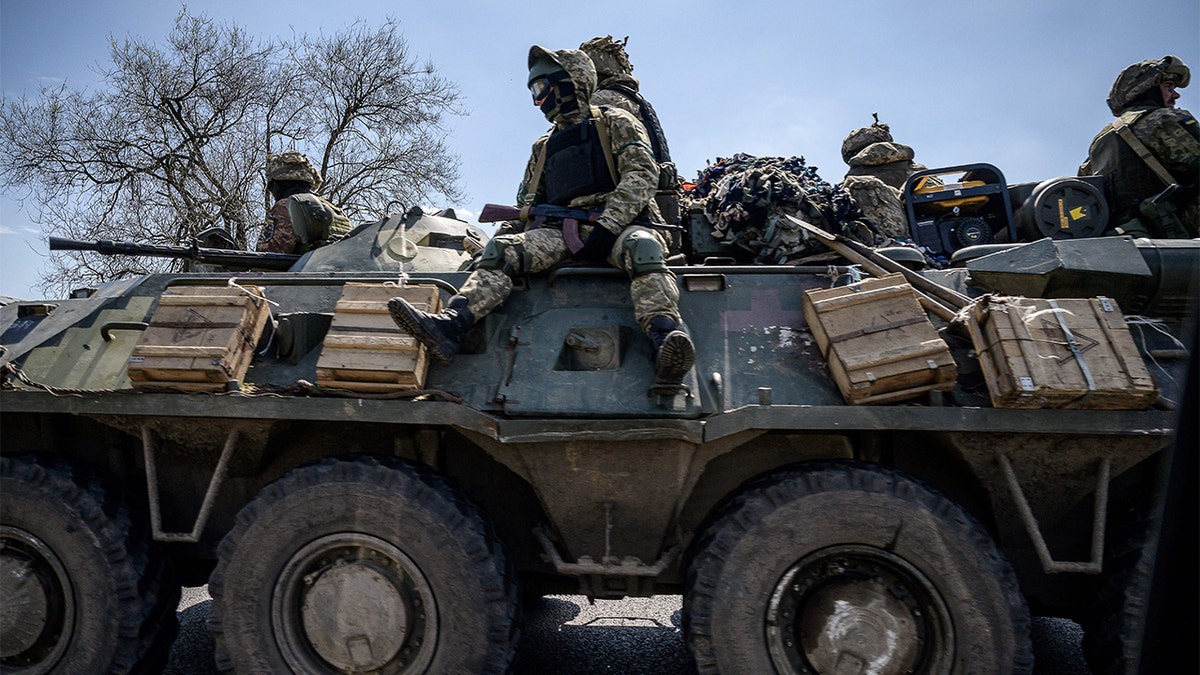 Ukrainian soldiers ride on an APC