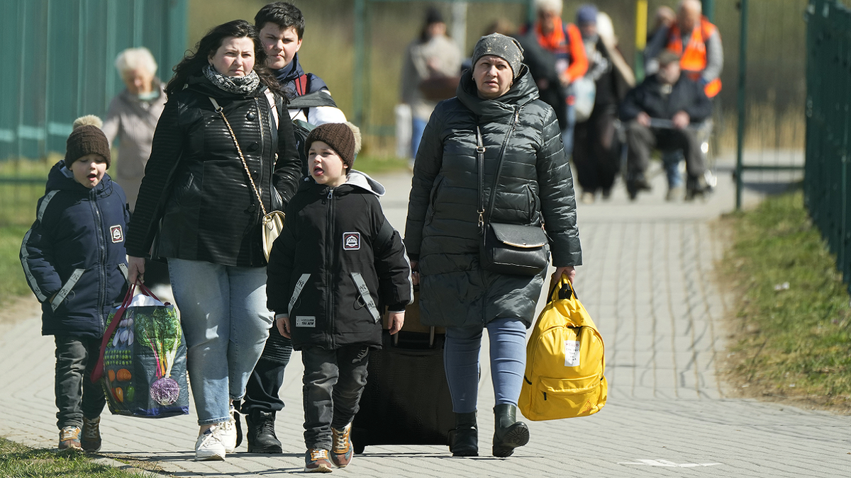 Refugees walk after fleeing the war from neighboring Ukraine at the border crossing in Medyka, southeastern Poland, on Friday.