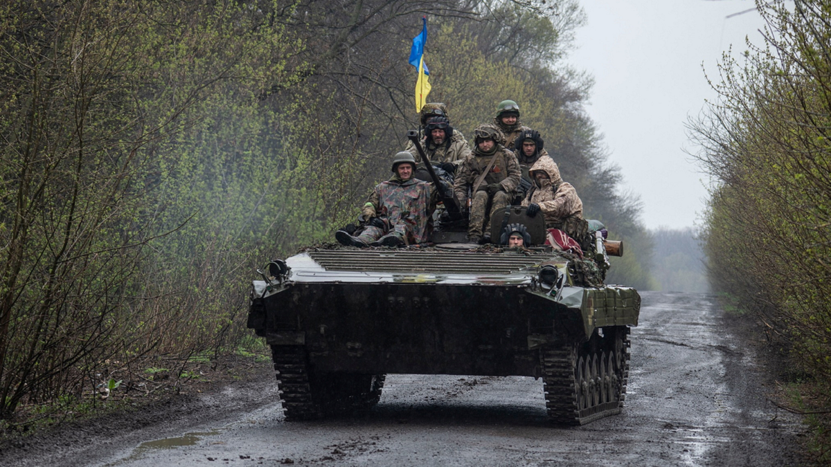 Ukrainian soldiers ride a combat vehicle during the war.