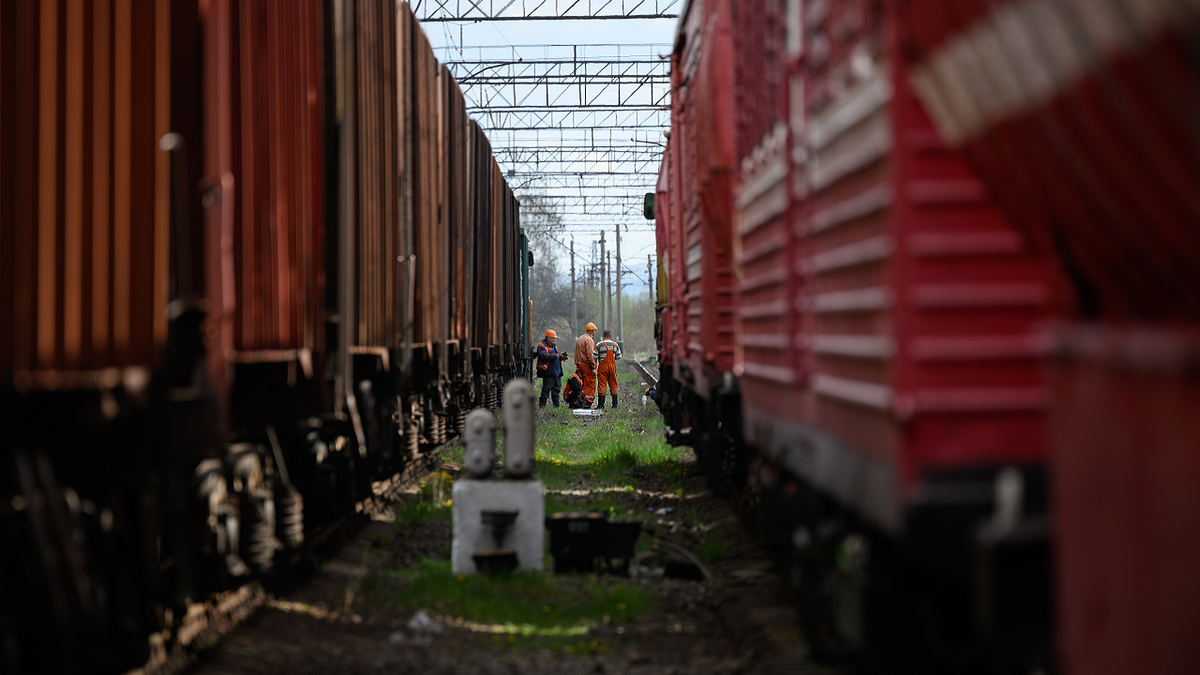 Rail workers wait between two train lines near the site of a missile strike near Lviv, Ukraine, on April 25, 2022.