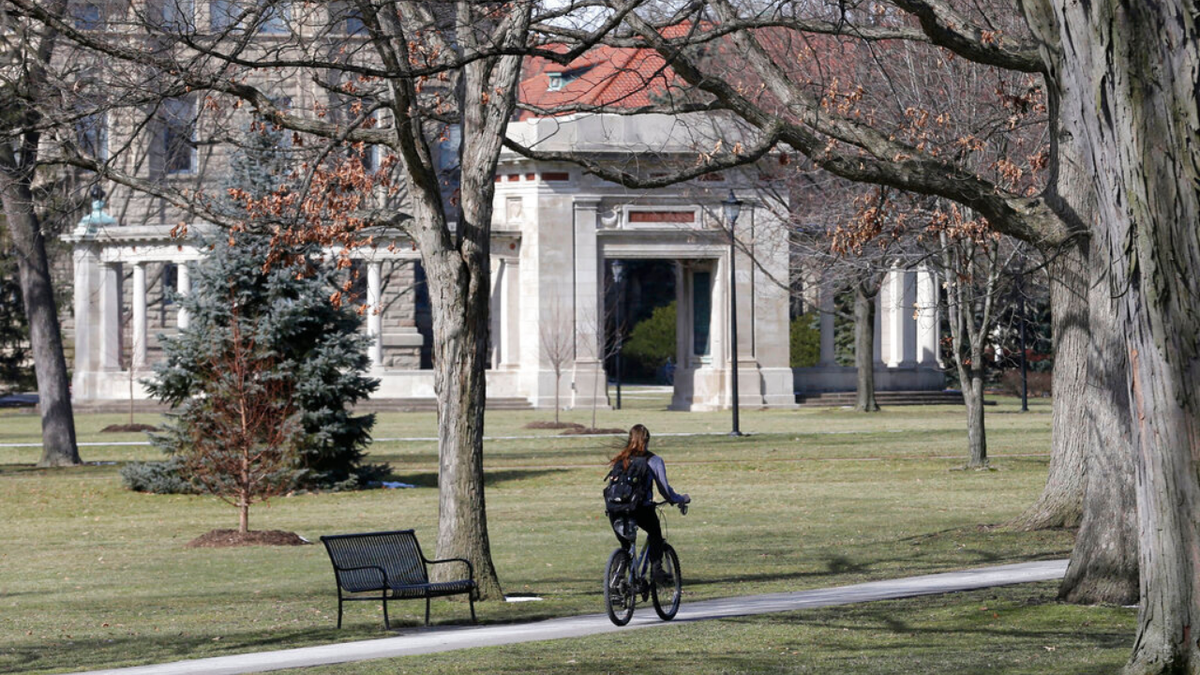 The photo shows a person riding a bicycle on the Oberlin campus