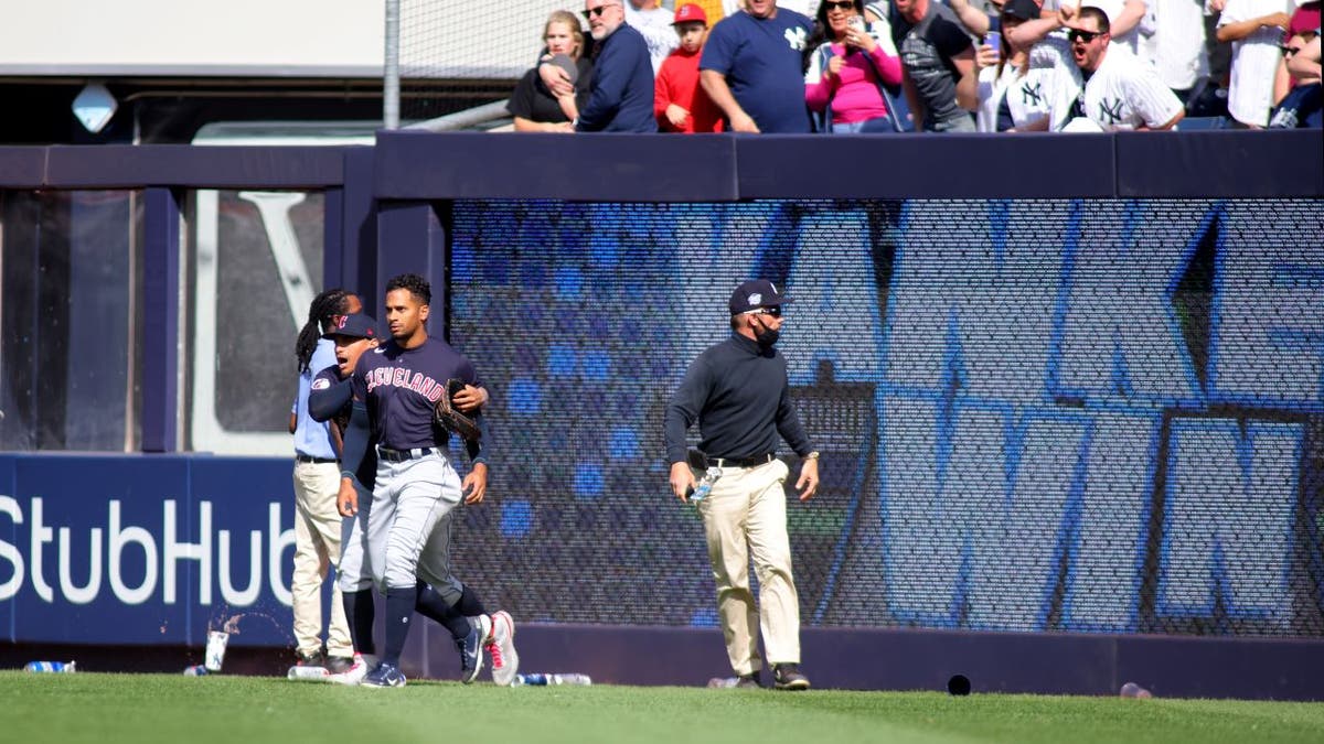 Oscar Mercado #35 of the Cleveland Guardians is restrained as fans throw debris on the field