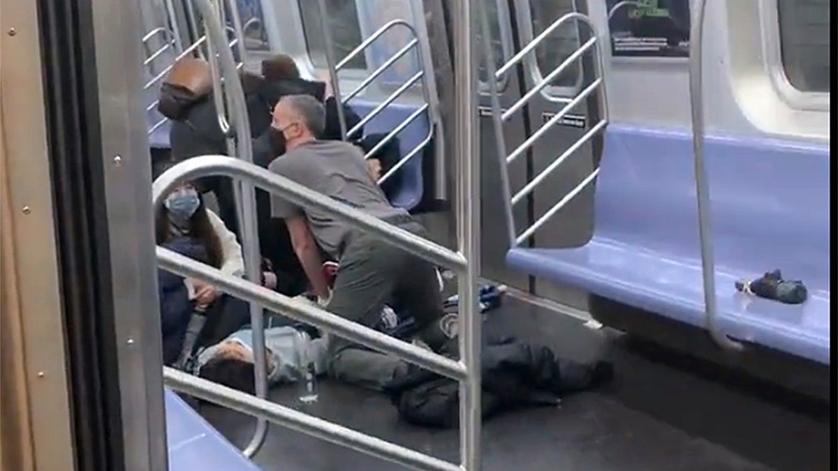 This photo provided by Will B Wylde, a person is aided in a subway car in the Brooklyn borough of New York, Tuesday, April 12, 2022. (Will B Wylde via AP)