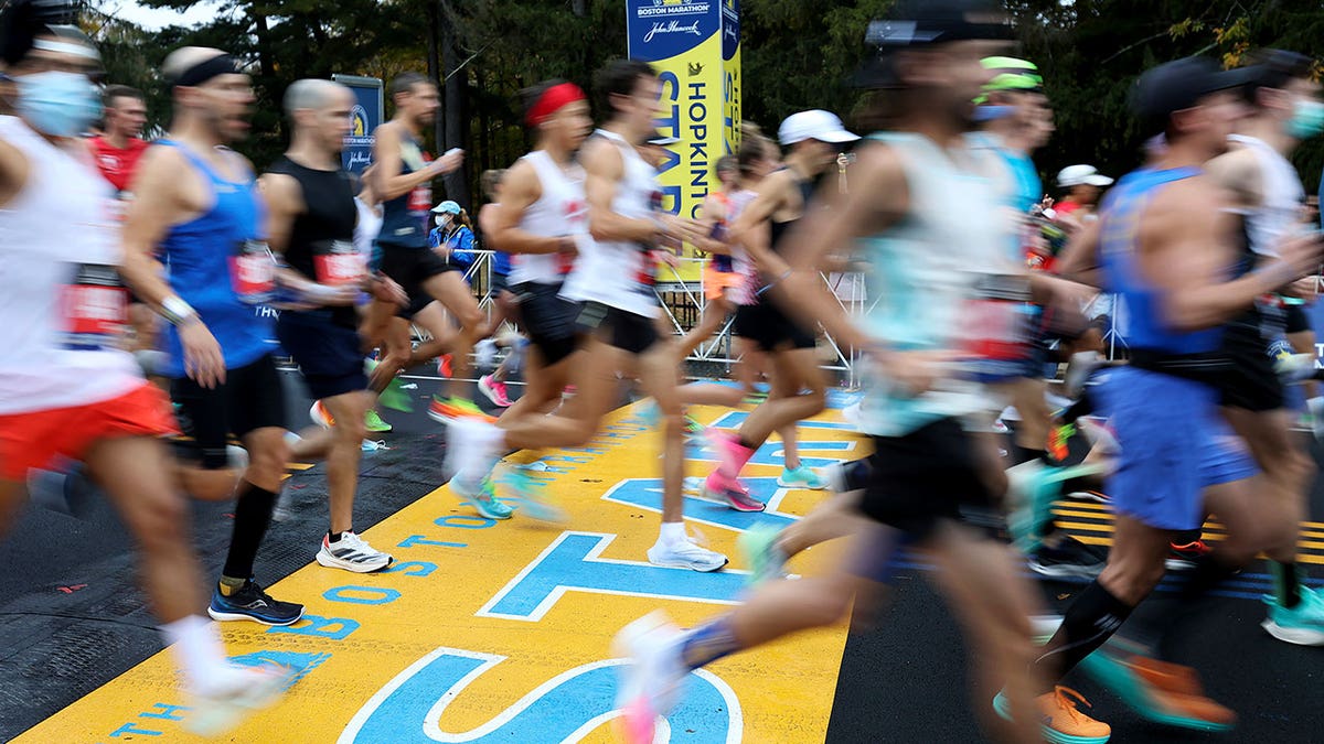 Runners cross the starting line of the 125th Boston Marathon, Monday, Oct. 11, 2021, in Hopkinton, Massachusetts.