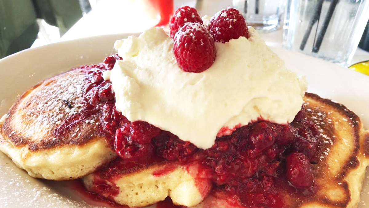 Raspberry-smothered pancakes topped with whipped cream