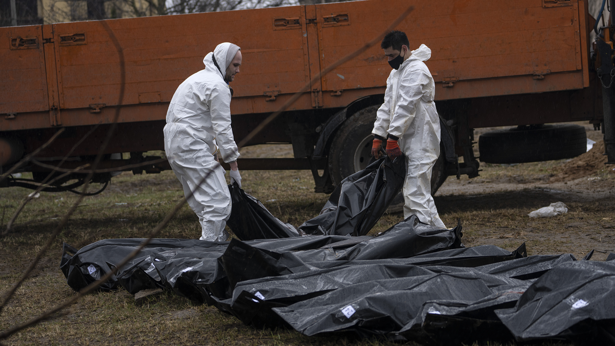 WARNING: GRAPHIC IMAGE: Cemetery workers carry a corpse of a man from a mass grave to be identified in a morgue in Bucha on Sunday.