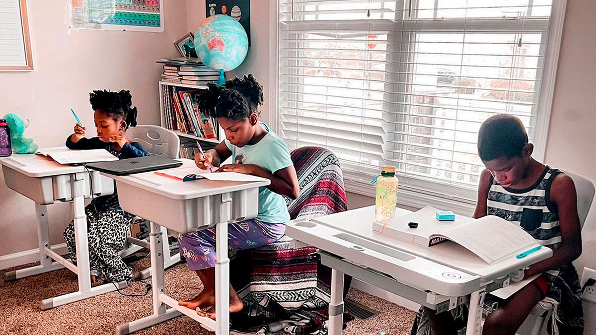 In this undated photo provided by Dalaine Bradley, Drew Waller, 7, Zion Waller, 10, and Ahmad Waller, 11, left to right, study during homeschooling, in Raleigh, N.C.