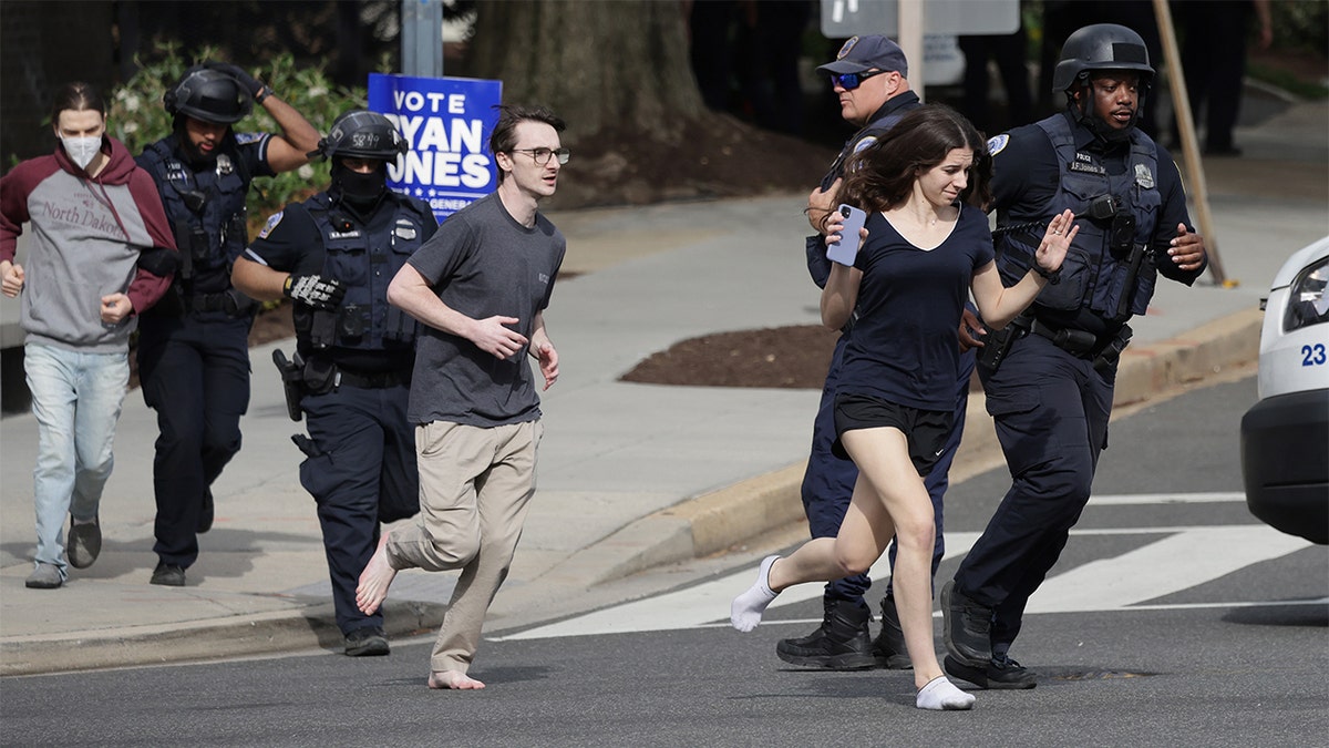 Metropolitan Police run as they escort people, some without shoes, away from a shooting scene in the northwest part of the city on April 22, 2022 in Washington, DC. 