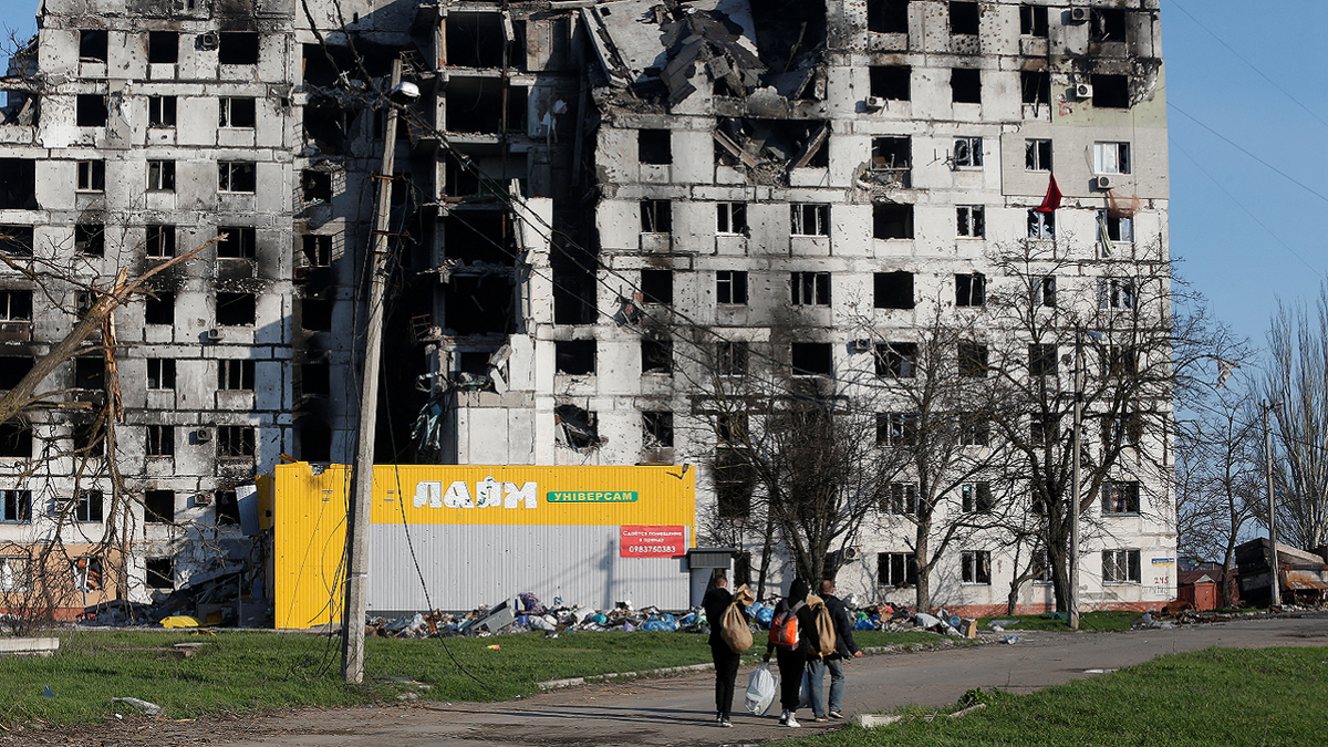 Local residents walk past a destroyed apartment building in Mariupol on Wednesday.