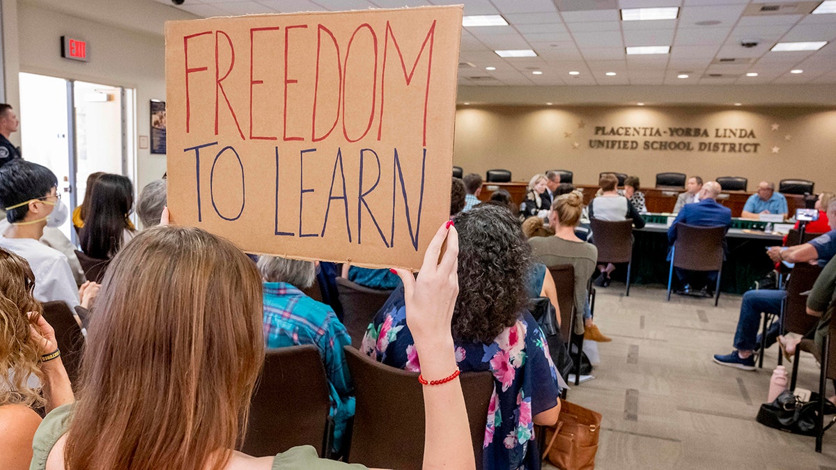 A student holds up a sign against banning CRT during the Placentia-Yorba Linda Unified School Board meeting in Placentia, California, on Wednesday, March 23, 2022.