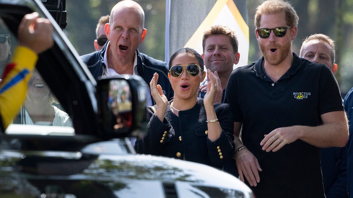 Prince Harry and Meghan Markle, Duke and Duchess of Sussex, scream as the Romanian competitor crosses the finish line of the Land Rover Driving Challenge.